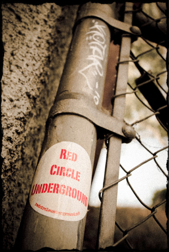 Sticker on fence pole: Red Circle Underground