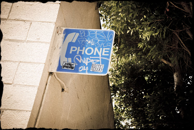 Old telephone sign with stickers and graffiti all over it
