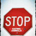 Stop sign with a sticker saying "eating animals"