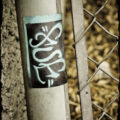 Sticker on side of pole of a chain link fence.
