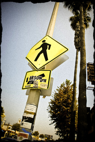 Crosswalk sign with sticker saying 