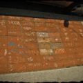 A section of the sidewalk lined with bricks that have graffiti on each brick.