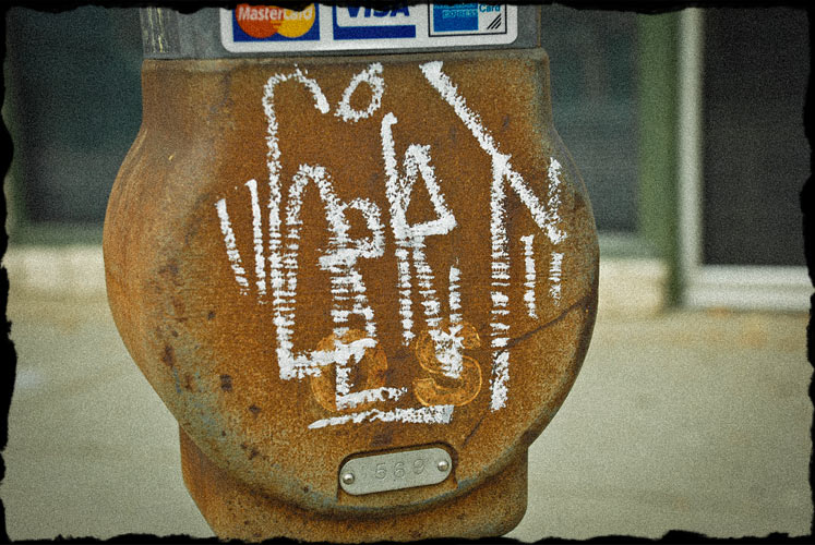 Weird lettering written on the backside of a rusty parking meter