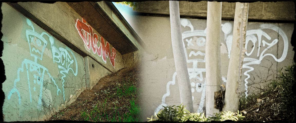 On the side of freeway overpass, graffiti of a robot and the word 
