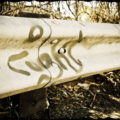 Graffiti on freeway side rail. Word "caught"