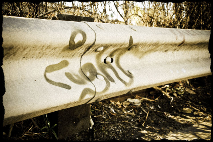 Graffiti on freeway side rail. Word 