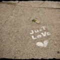 A heart and "just love" spray painted on the sidewalk